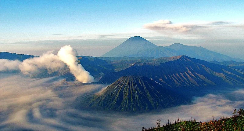 Vast expanse of the Sea of Sand surrounding Mount Bromo, resembling a lunar landscape with scattered shrubs