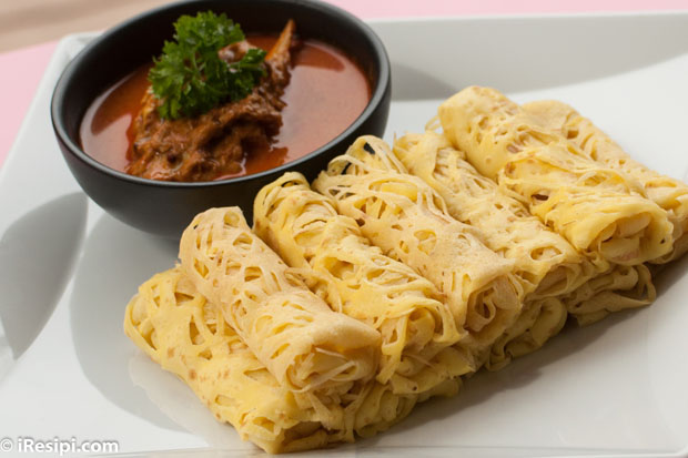 Roti Jala yang digulung rapi, siap disajikan bersama kuah kari yang menggugah selera, mencerminkan warisan kuliner Melayu yang kaya dan penuh cita rasa